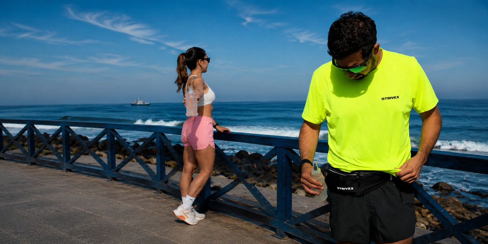 Dos deportistas utilizando los accesorios strivex, la botella soft flask y el banano running move negro